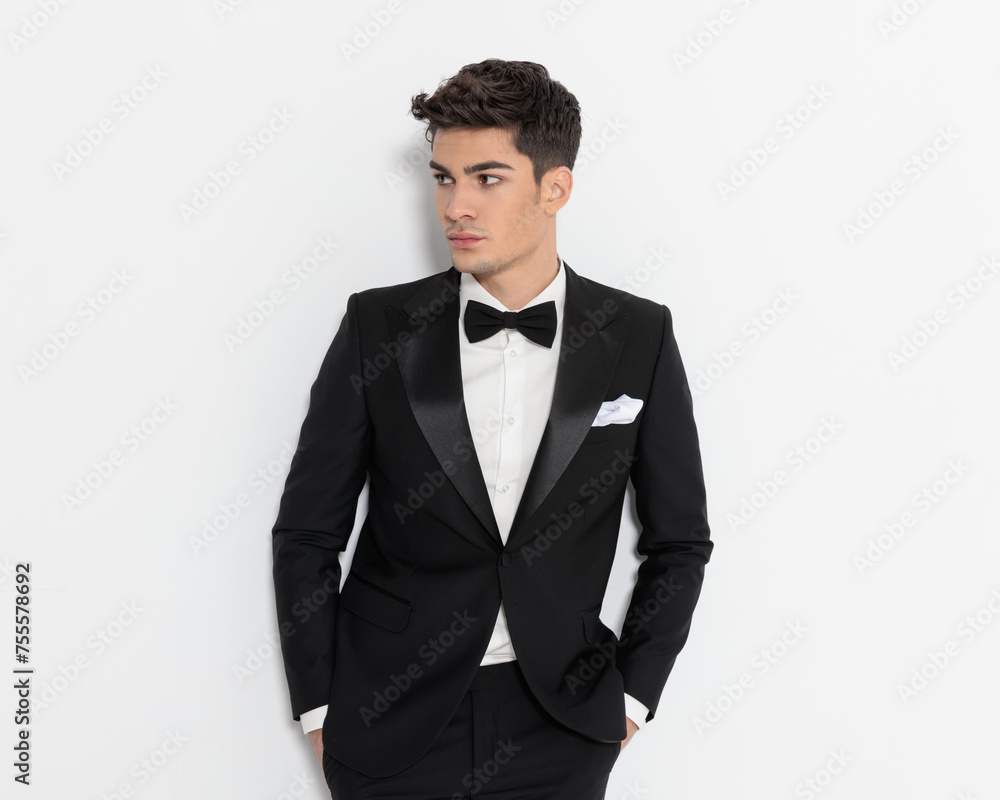 confident elegant groom in black tuxedo holding hands in pockets confident elegant groom in black tuxedo holding hands in pockets