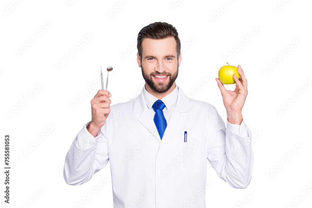 Portrait of successful toothy dentist in white lab coat, blue tie, holding equipments and green apple in hands, isolated on grey background, recommend taking care about teeth Portrait of successful toothy dentist in white lab coat, blue tie, holding equipments and green apple in hands, isolated on grey background, recommend taking care about teeth