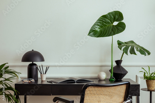 Billede på lærred Elegant composition of living room interior with black desk, rattan armchair, vase with leaves, stylish sculpture, rack with books and personal accessories