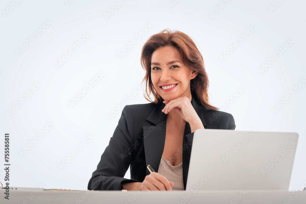 Studio shot of an attractive mid aged woman sitting at desk and using laptop against isolated white background Studio shot of an attractive mid aged woman sitting at desk and using laptop against isolated white background