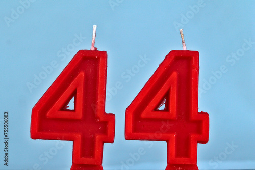 close up on a red number forty fourth birthday candle on a white background.
 photo