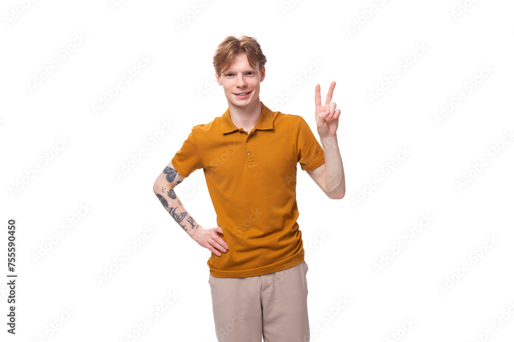 young red-haired caucasian student man with a tattoo dressed in a mustard t-shirt gesturing young red-haired caucasian student man with a tattoo dressed in a mustard t-shirt gesturing