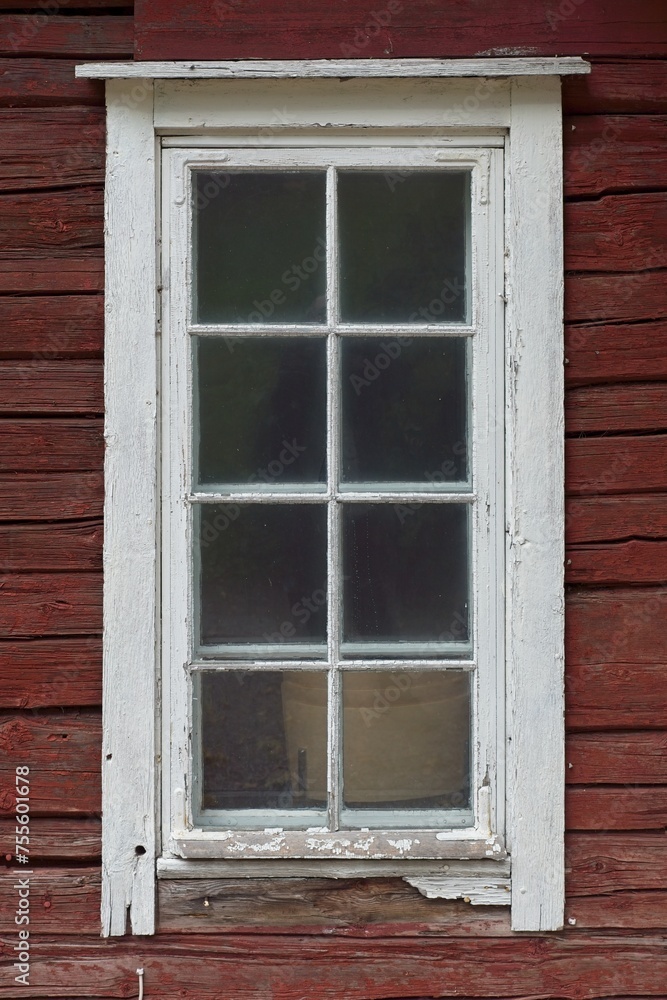White framed window on a old red painted wooden building.
