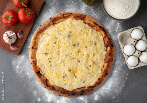 Four cheese pizza with tomatoes, eggs and flour over stone background