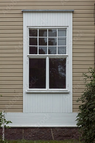 Old white framed window on wooden building.