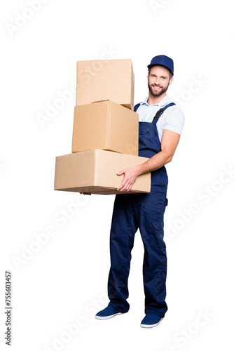 Full size fullbody portrait of attractive cheerful deliver in blue uniform with stubble, looking at camera having three big boxes in arms, isolated on grey background