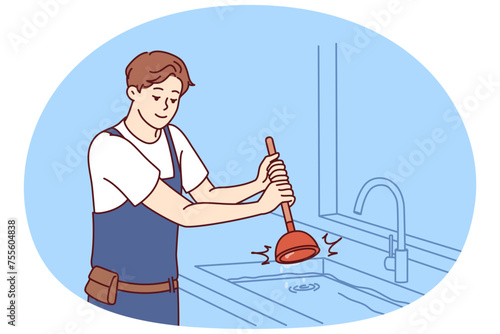 Man plumber uses plunger to clear blockage in sink in kitchen or bathroom. Guy working as plumber is dressed in overalls and is engaged in elimination breakdown associated with debris stuck in pipe