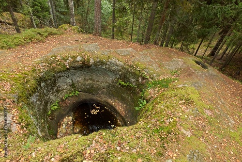 Cylindrical Talvia Giant´s kettles (giant´s cauldron, moulin pothole, or glacial pothole) drilled in solid rock in forest in autumn with leaves on the ground, Lohja, Finland. photo