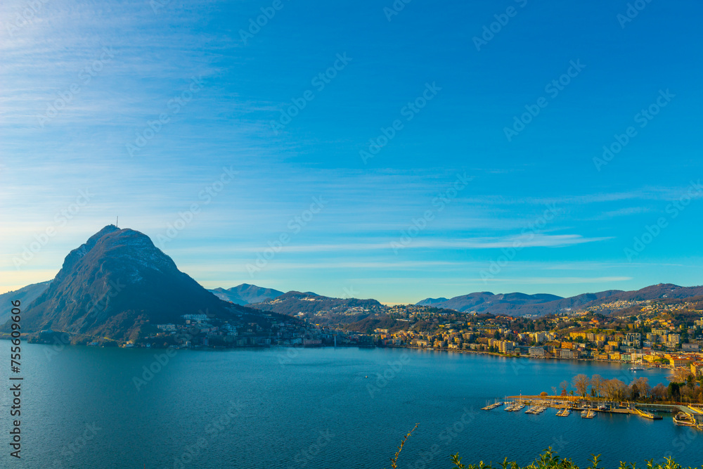 Sunlight on Lake Lugano and City with Mountain San Salvatore and Blue Sky in Lugano, Ticino in Switzerland.