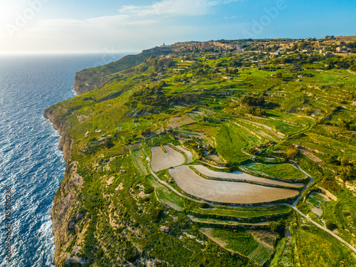 Aerial drone view of green fields, cliffs and hills of Maltese island, nature landscape, blue sky. Mediterranean sea