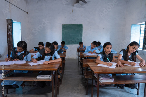 Group of indian village students in school uniform sitting in classroom doing homework, studying. Education concept