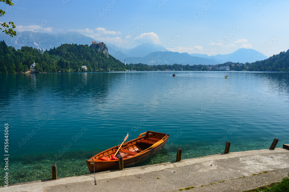 Cloudy summer day by the lake Bled in Slovenia with its clear turquoise water, famous baroque church and wooden rowing boat