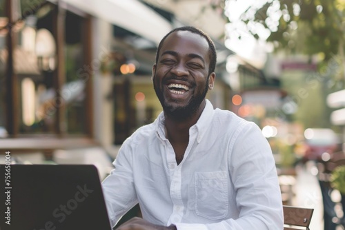 Laughing black man sitting at the table with laptop, business and technology concept.