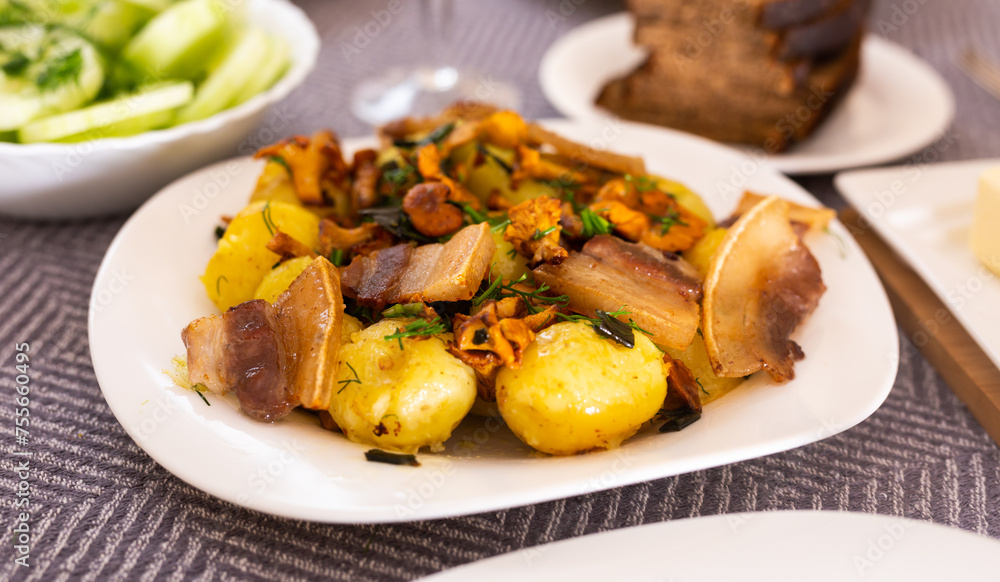 Baked potatoes with chanterelles and bacon served with herbs on white plate Baked potatoes with chanterelles and bacon served with herbs on white plate