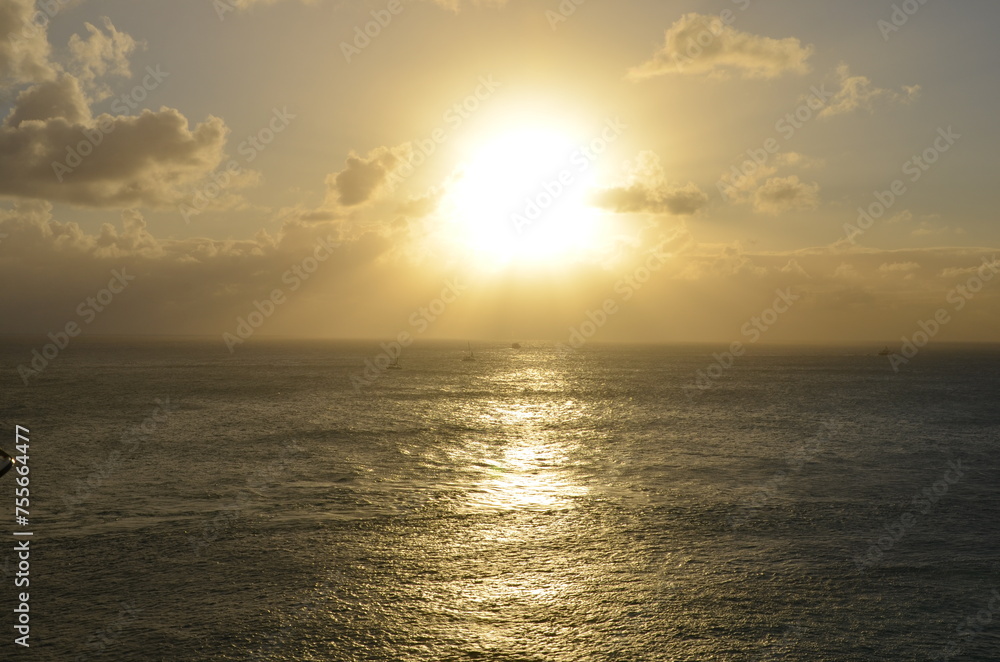 Obraz premium Golden sunset at sea, sailing boat on horizon, reflections of sunrays, sunset sky with clouds