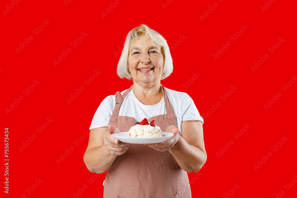 Housewife female chef cook confectioner or baker in apron white t-shirt holding in hand cake on plate isolated on red background in studio. Food concept
