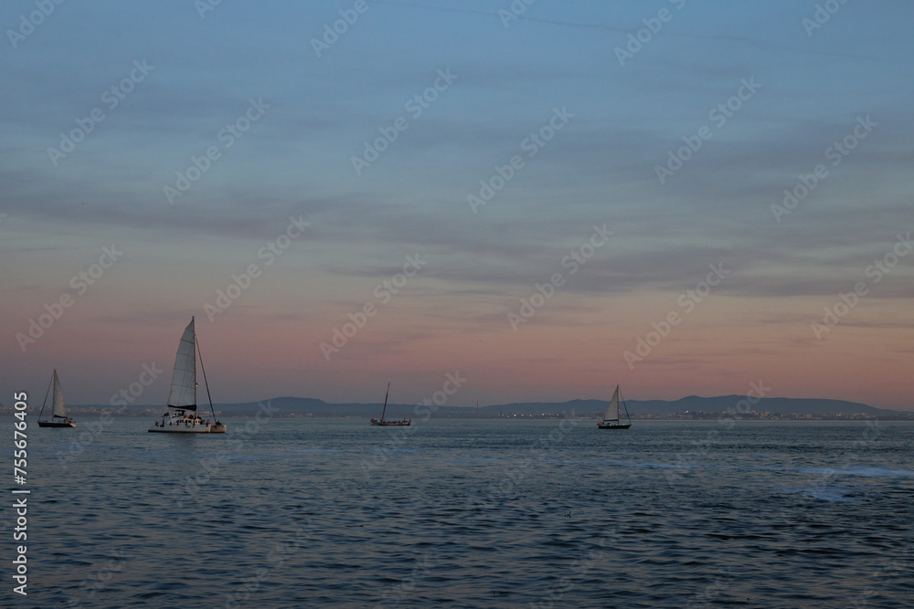Sailboats on a vast sea during sunset