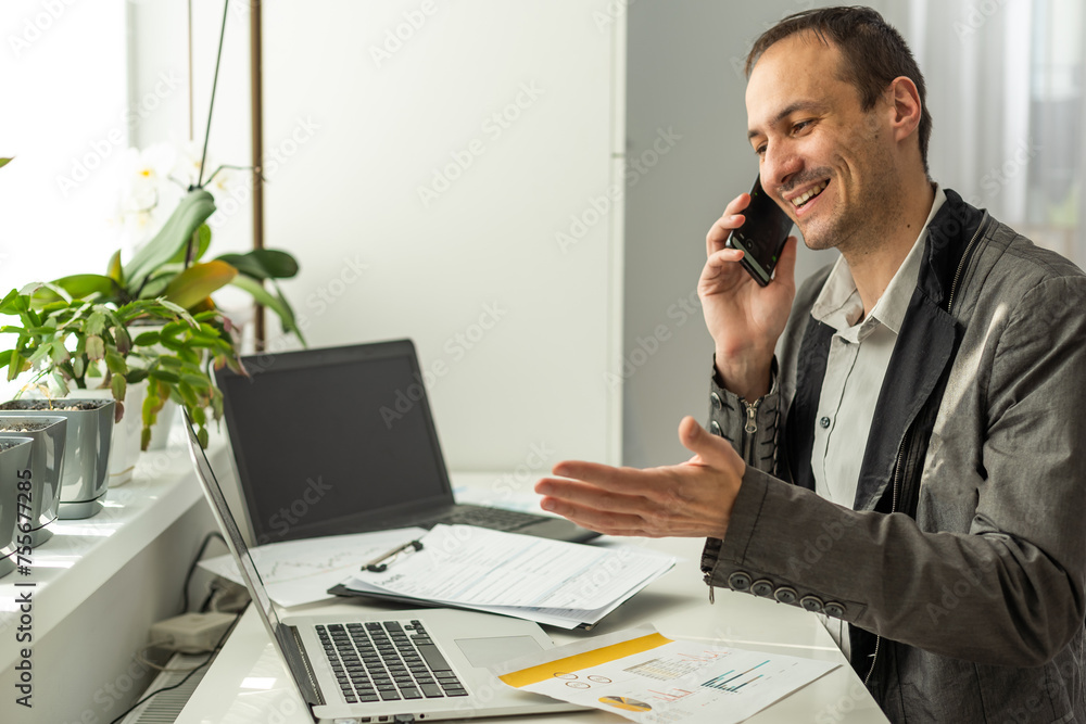 Happy successful busy caucasian man in a suit, company employee, top manager, boss, sitting in the office, talking on the phone with a colleague or client, resolves work issues, smiling Happy successful busy caucasian man in a suit, company employee, top manager, boss, sitting in the office, talking on the phone with a colleague or client, resolves work issues, smiling