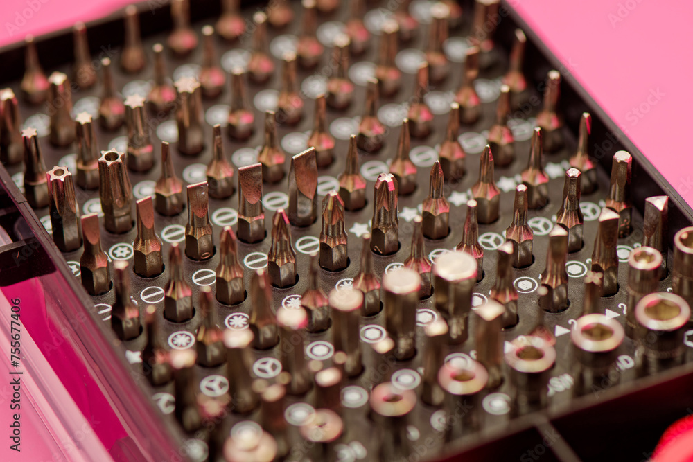 Screwdriver bit set close up photo on a pink background. Bits for screwdriver in box. Repairing smartphone concept. Advertising purposes Screwdriver bit set close up photo on a pink background. Bits for screwdriver in box. Repairing smartphone concept. Advertising purposes