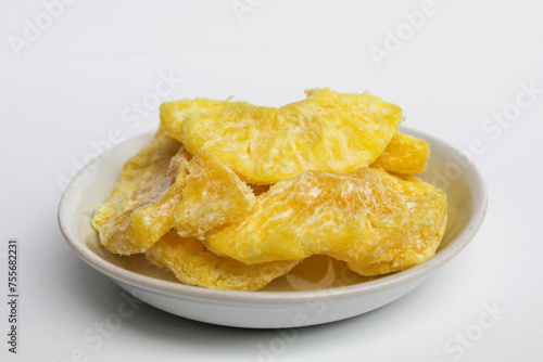 Dried pineapple sweets. Candied and dried pineapple. On small white plate. Isolated on white background