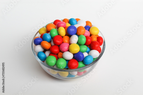 Biscuit balls coated by colorful chocolate. On transparent glass bowl. Isolated on white background