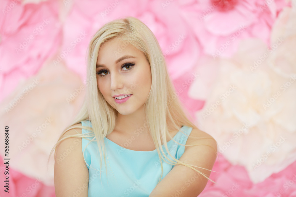 Pretty young woman in dress poses near wall with big flowers in studio Pretty young woman in dress poses near wall with big flowers in studio