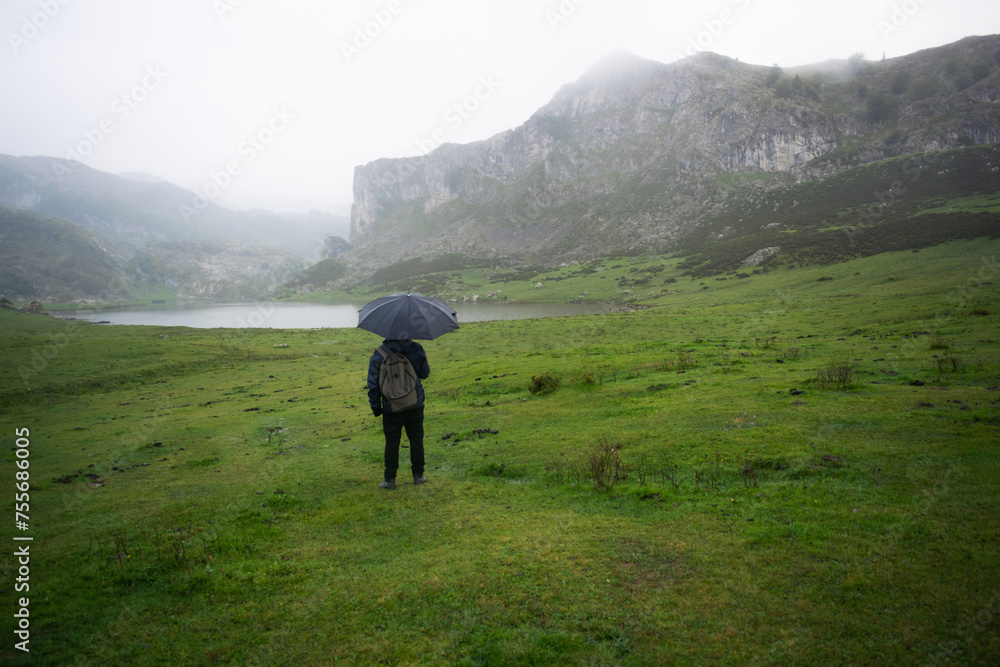 Man with raincoat and umbrella in Los Lagos de Covadonga. Asturias - Spain