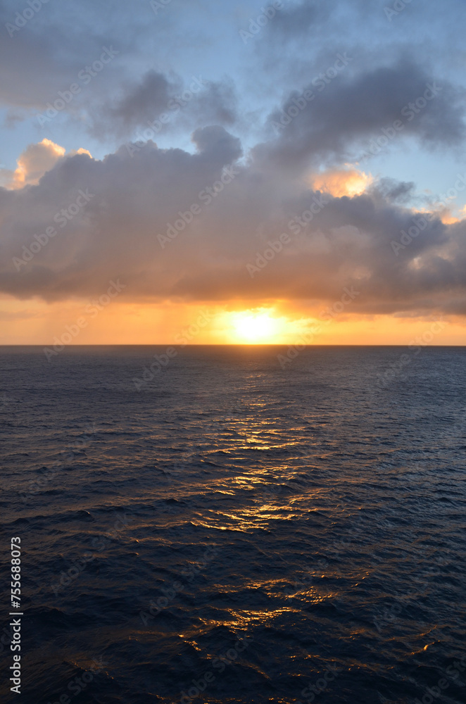 Orange sunset at set, reflections of sun rays on rippled water surface, cloudy sky, concept for traveling and tourism 