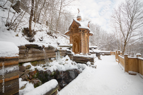 Wooden old-style structure and fountain in Russian Orthodox Monastery at winter