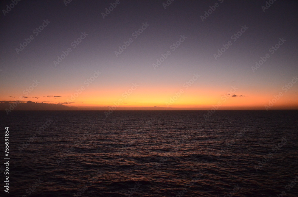 Sunset at sea, reflections of sun rays on rippled water surface, clear sky, concept for traveling and tourism