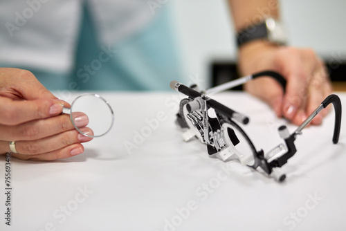 Hands of female doctor, ophthalmic glasses and lens, shallow dof