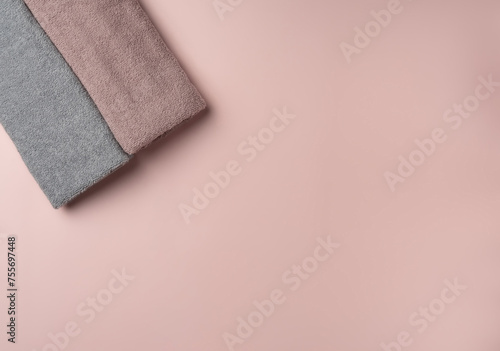 Two towels on pastel pink background.