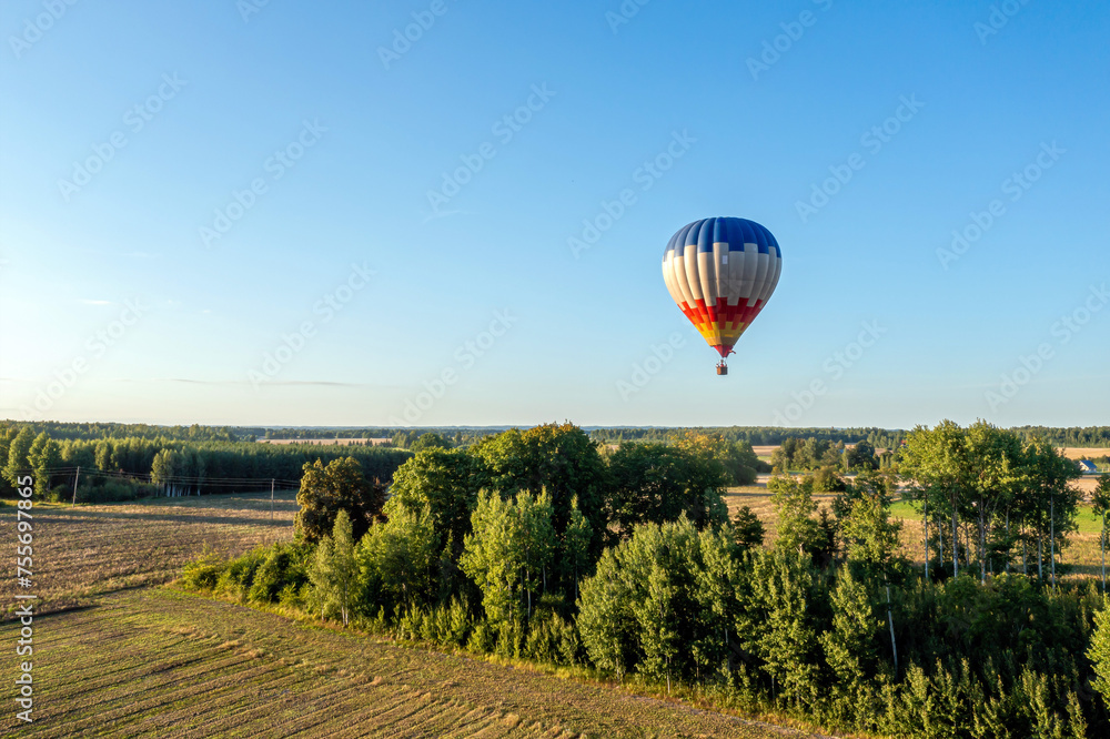 Hot air balloon flying over the field in the evening. Beautiful summer landscape.