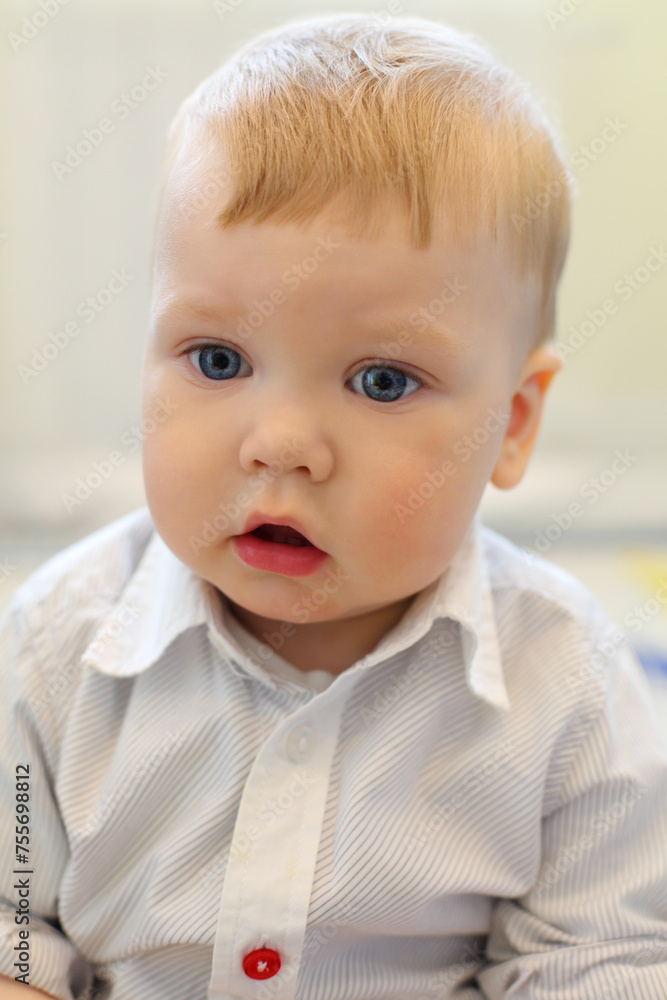 Handsome little funny blonde boy in white shirt, close up portrait