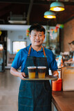 Asian ,Korean ,Man barista Holding an Ice Americano Coffee and Matcha Latte on a Wooden Tray