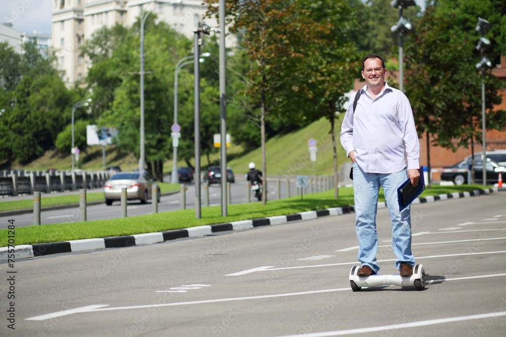 Happy man with folder rides GyroScooter on street at summer day Happy man with folder rides GyroScooter on street at summer day
