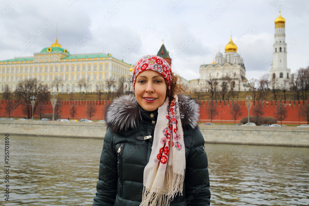 Womand stands near river, Grand Kremlin Palace nad Kremlin walls in Moscow at sring