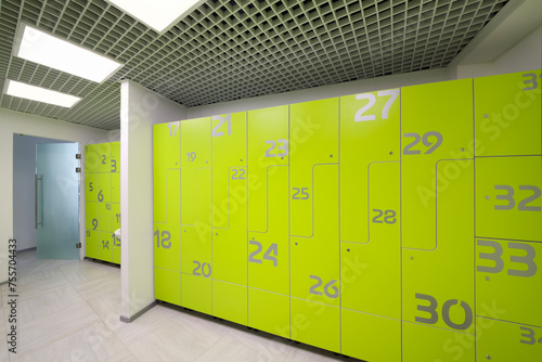 Empty bright modern cloakroom in gym with many green lockers photo