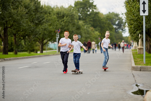 Two boys and girl ride skateboard and walk on street © Pavel Losevsky