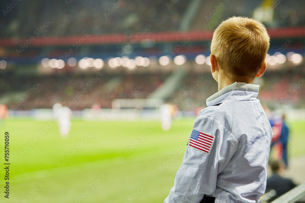 Obraz premium Little boy watch soccer game at stadium, rear view