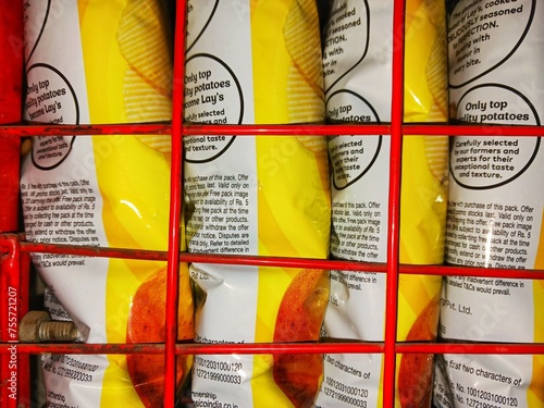 Picture of chips packets arranged tightly in a row inside a rack in a shop which can be used for illustrating super market, shop, oily foods, fast food, processed food, crowd, increasing population. 