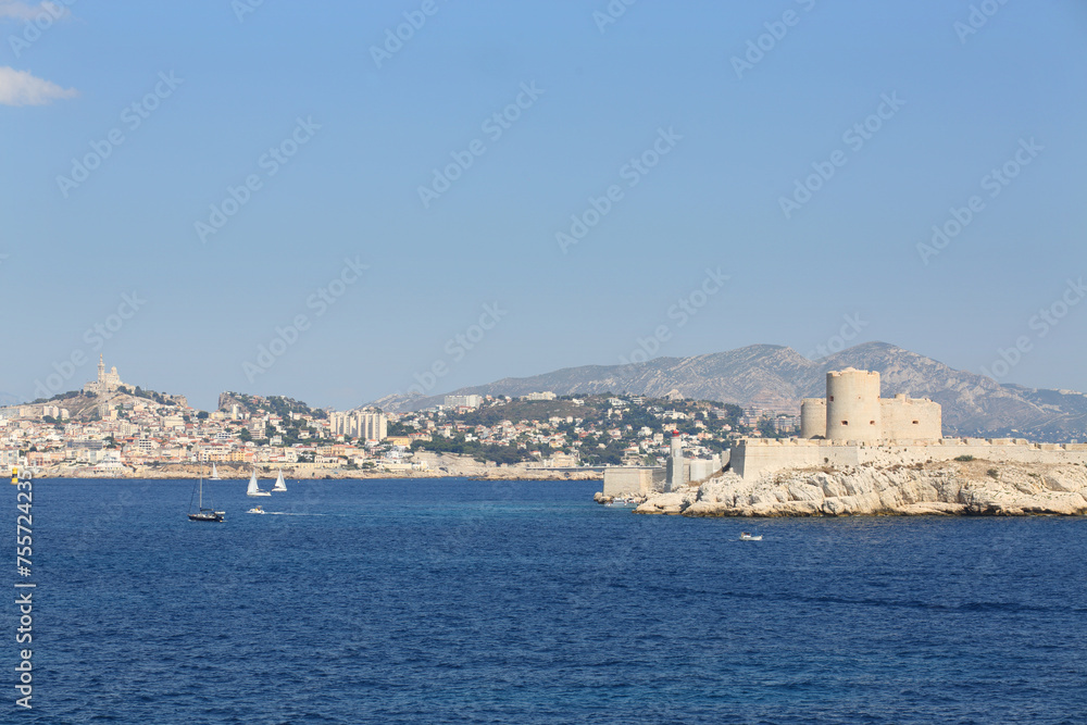Boats sail near Chateau IF fortress on island and coastal city at summer, Marseille, France