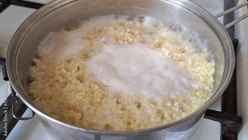 Millet porridge boiling in a steel pan closeup, steaming hot water. Cooked on a gas stove Millet porridge boiling in a steel pan closeup, steaming hot water. Cooked on a gas stove