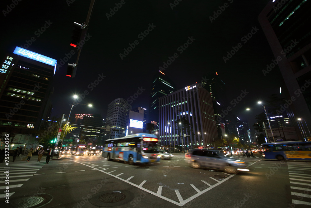  People crossing road on crosswalk and cars move at night. Pedestrians in Seoul can now more safely get to streets of central areas
