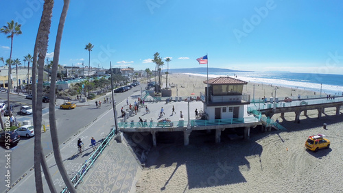  People walk by Manhattan Beach Pier along sandy beach at sunny day. Aerial view. Pier was built in 1920. © Pavel Losevsky