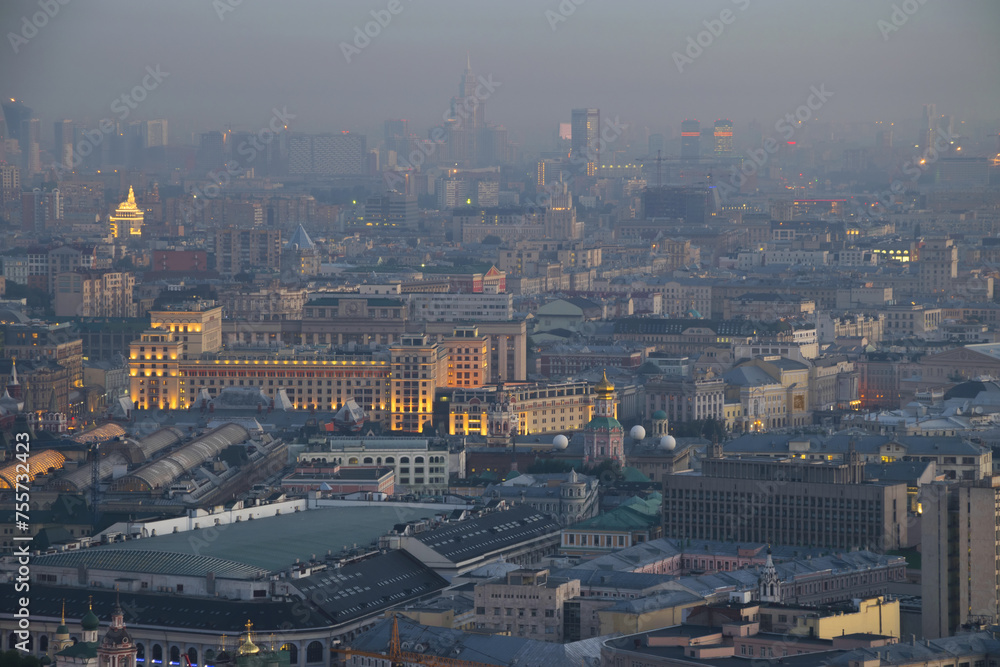 Illuminated buildings and roofs in fog at summer night in Moscow, Russia, Tverskoy area