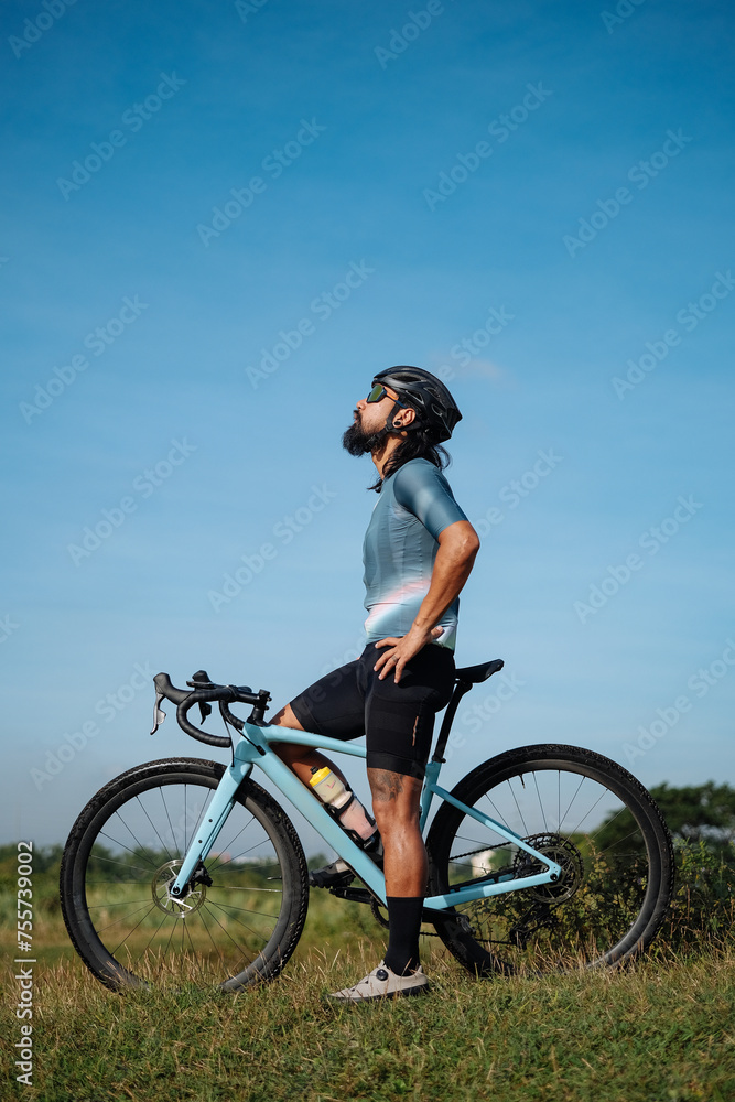 A middle aged bearded cyclist with his gravel bike looking up. A middle aged bearded cyclist with his gravel bike looking up.