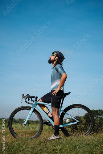 A middle aged bearded cyclist with his gravel bike looking up.