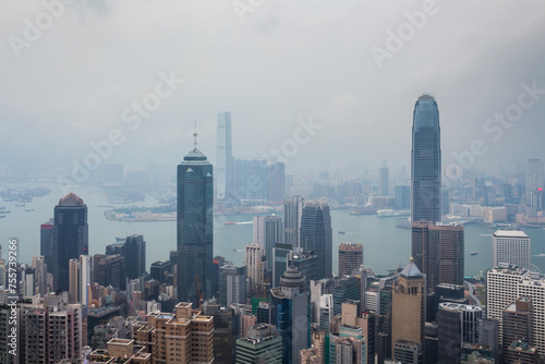 Tall skyscrapers on sea shore with ships in business area in fog in Hong Kong, China, view from Queen Garden