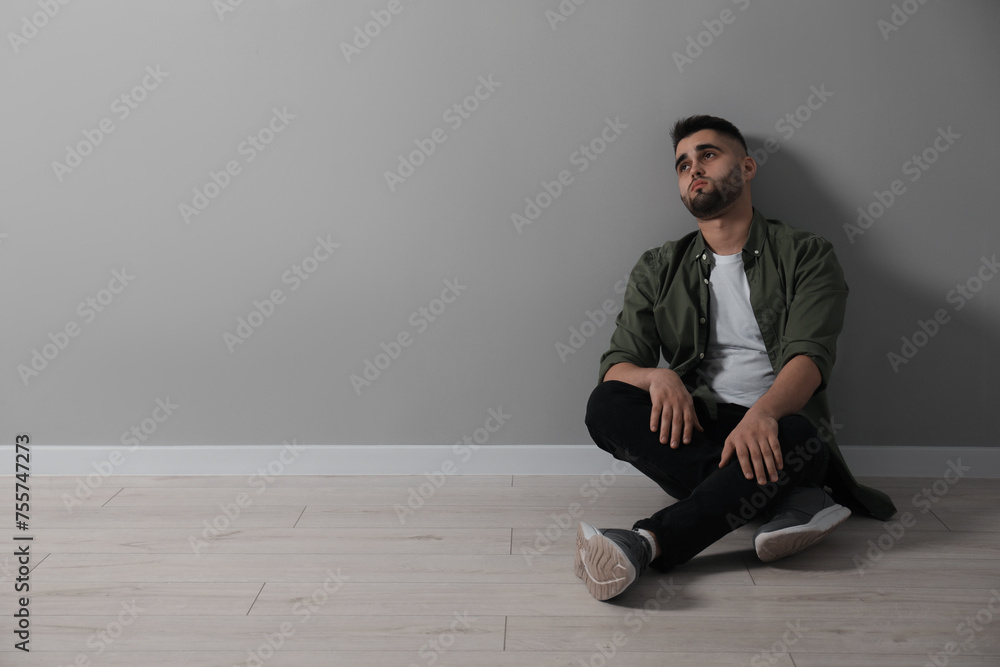Sad man sitting on floor near light grey wall. Space for text Sad man sitting on floor near light grey wall. Space for text